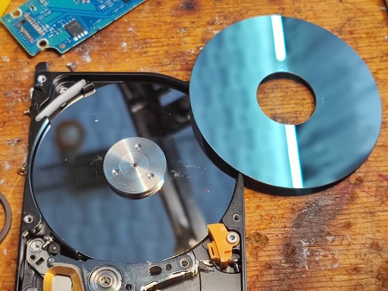 Opened Hard Drive with Visible Platter Opened hard drive with visible platter and electronics on a wooden background.