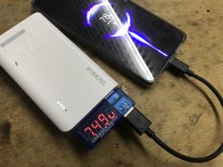 Powerbank Romoss ładuje smartfon, pomiar prądu przez tester USB pokazuje 7,49V.