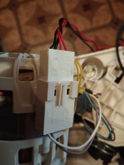 Zbliżenie na złącze elektryczne z czterema pinami, z dwoma czerwonymi i czarnymi przewodami podłączonymi do silnika.