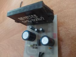 Płytka PCB z czarnym transformatorem UNITRA TELPOD GM‑026/2 i kondensatorami na tle drewna