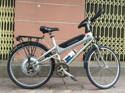 Elektryczny rower Mercedes-Benz z silnikiem umieszczonym na tylnym kole, stojący przed metalową bramą.