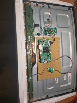 Wnętrze monitora z widocznymi komponentami elektronicznymi na drewnianej podstawce.