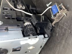 Zbliżenie na mechanizm z niebieską taśmą wokół elektromagnesu wewnątrz urządzenia.