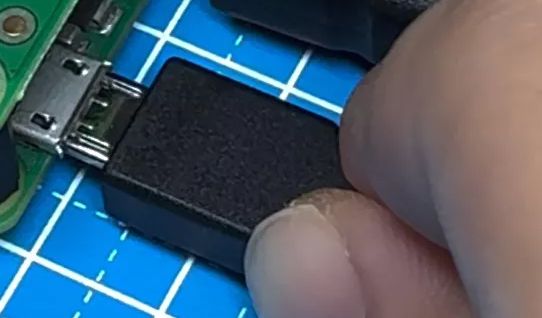 Zbliżenie na dłoń wkładającą wtyczkę micro USB do gniazda w urządzeniu elektronicznym.