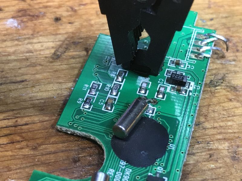 Zdjęcie zbliżeniowe PCB klawiatury bezprzewodowej z klipsem programatora.