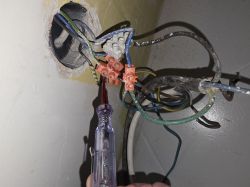 Plątanina kabli w puszce elektrycznej z podświetlonym próbnikiem napięcia