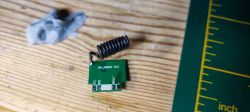 RF module with coil and markings WH_RXD05 V0.2 on a wooden surface.