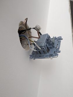 Wyłącznik elektryczny z widocznymi podłączonymi przewodami wystający ze ściany.