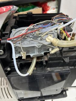 Wnętrze ekspresu Delonghi z widocznymi przewodami i grzałką pary