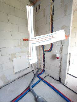 Instalacja hydrauliczna z kolorowymi rurami i schematem narysowanym na ścianie