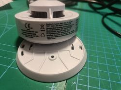 Close-up of a Tuya smoke detector with visible labels on a green mat.