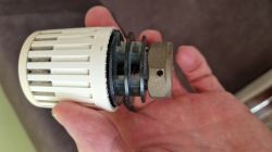 Termostatyczna głowica Danfoss z lat 90. z widocznym mocowaniem na ręce.