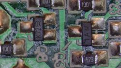 Zbliżenie na elementy SMD na zielonej płytce PCB, w tym rezystory i diody, z widocznymi oznaczeniami K72X, 1AM, 1001 i 473.