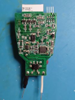 Zielona płytka PCB z elementami SMD na niebieskim tle, z dwoma przewodami u dołu