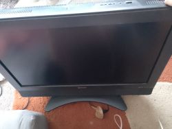 Telewizor Sharp z czarnym ekranem stojący na dywanie, nie włącza się