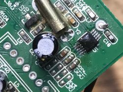 Close-up of PCB showing capacitor, metal can resonator, and SMD chip with soldered pins