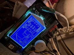 Solar collector controller with illuminated LCD display and connected wires.