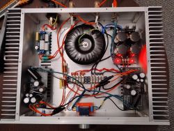 Widok wnętrza zmontowanego wzmacniacza audio z transformatorem toroidalnym i elektroniką