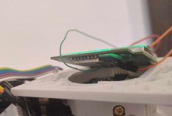 Printed circuit board with attached wires on a white base.