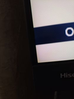Zbliżenie na ekran telewizora Hisense z delikatnym zielonym odcieniem w rogu.