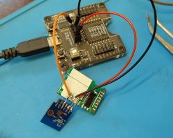 Close-up of an ESP development board programmer connected to an electronic module with a blue PCB.