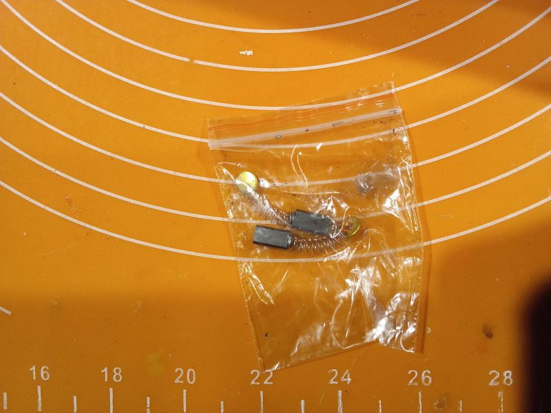 Zestaw szczotek węglowych w przezroczystym woreczku na pomarańczowej podkładce