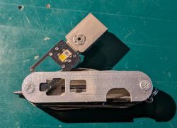 Otwarty scyzoryk z metalową okładziną i modułem LED oraz pendrive’em na zielonej macie