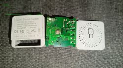 Disassembled mini smart WiFi switch with visible PCB and casing parts