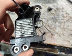 Zużyty regulator napięcia BOSCH trzymany w ręce, widoczne zabrudzenia i ślady eksploatacji