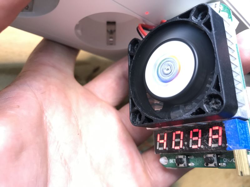 USB power strip load test with cooling fan and amp meter at 4.03 A Cooling fan with meter showing 4.03 A held near power strip with USB ports