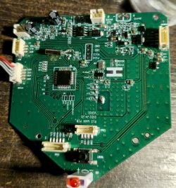 Płytka PCB z elementami SMD, złączami i diodą LED, widok z góry na drewnianym blacie