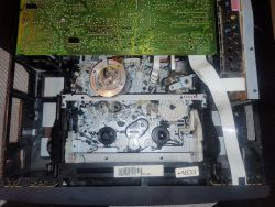 Wnętrze magnetowidu VHS z widocznym mechanizmem i płytką drukowaną u góry