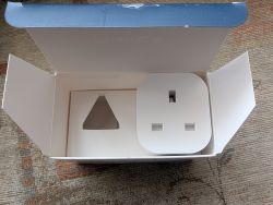 Inside of the box with a minimalist plug Inside of an open box containing a single, minimally designed electronic plug.