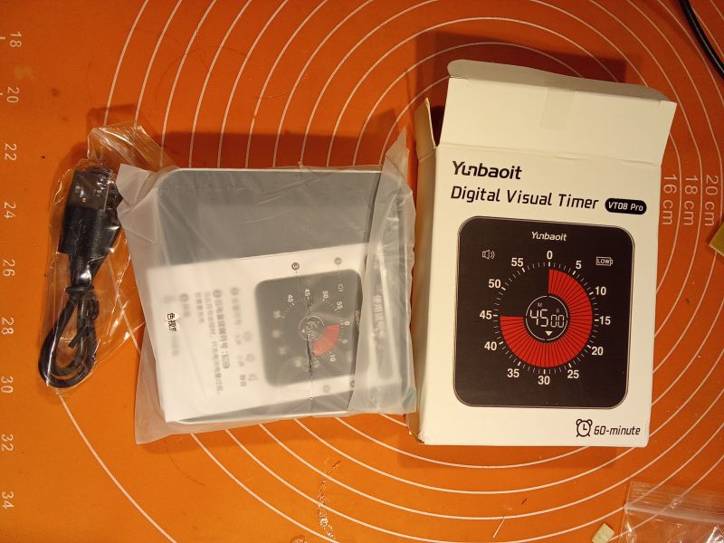 Elektroniczny minutnik Yunbaoit VT08 Pro z kablem USB i instrukcją na pomarańczowym tle.