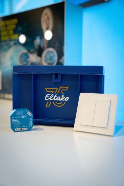 Blue Eltako box with a small electronic module and a white double light switch on a tabletop