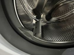 Bęben pralki z widoczną uszczelką gumową i elementem plastikowym.