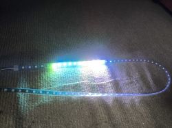 LED strip emitting various colors, arranged in a loop on a brown carpet.