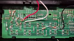 Close-up of a circuit board with a red, white, and black wire, and several resistors.