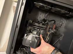 Wnętrze obudowy komputera z podzespołami, suchą ręką wyjmowaną kartę graficzną Radeon.