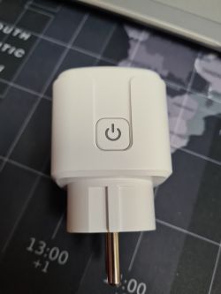 White smart plug with a visible power button on a dark background.