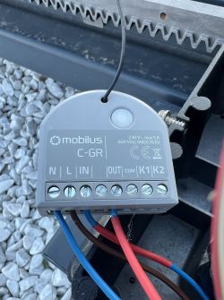 Moduł sterujący Mobilus C‑GR z podłączonymi przewodami, zamocowany przy listwie zębatej bramy