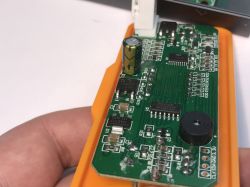 Zbliżenie na płytkę drukowaną stacji lutowniczej T12OAS z widocznymi podzespołami elektronicznymi, w tym kondensator, układy scalone i buzzer.