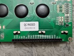 Dolna część tylnej strony zielonego modułu LCD z pinami i etykietą QC PASSED