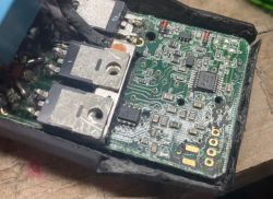 Płytka elektroniki w czarnej obudowie z dwoma dużymi tranzystorami i układem scalonym