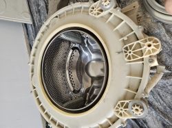 Zdjęcie bębna pralki Hoover wyjętego z obudowy, widoczny plastikowy kołnierz i metalowy bęben.