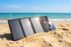 Foldable solar charger set up on a sandy beach near the sea
