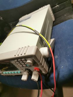 Generator sygnału lub oscyloskop cyfrowy z podłączonymi przewodami, ustawiony na fotelu.