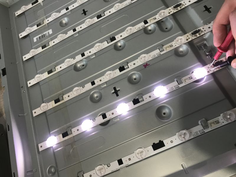 Testing LED Diodes in TV Backlight Inside of a TV with exposed LED backlight strips, connected to a power supply for testing the diodes.
