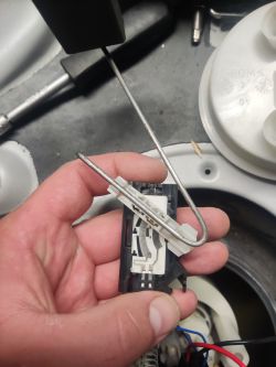 Zbliżenie na czujnik paliwa z metalowym prętem i przewodami w dłoni.