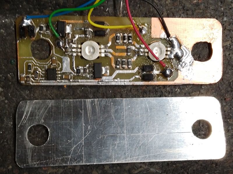 Płytka PCB z elementami elektronicznymi i przewodami na ciemnym tle.